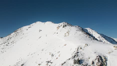 flying over snow covered mountain peak into plateau reveal, establisher
