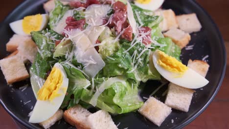 a delicious fresh healthy caesar salad spinning on a black plate with close up