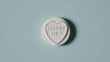 heart candy with marry me message on blue background