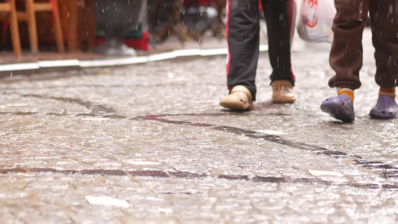People walking on a rainy cobblestone street