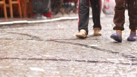 people walking on a rainy cobblestone street