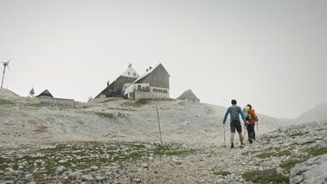 背着背包和徒步杆的徒步旅行者走向山小屋