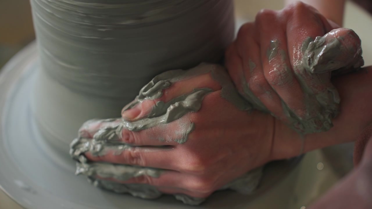 Stable pottery shaping. Craftsman molds ceramic form carefully. Hands balance as artist shapes moist ceramic on wheel. Fingers precisely press and rotate damp clay to create symmetrical vessel