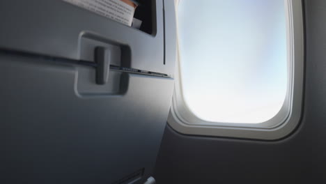 person opening airplane window shade