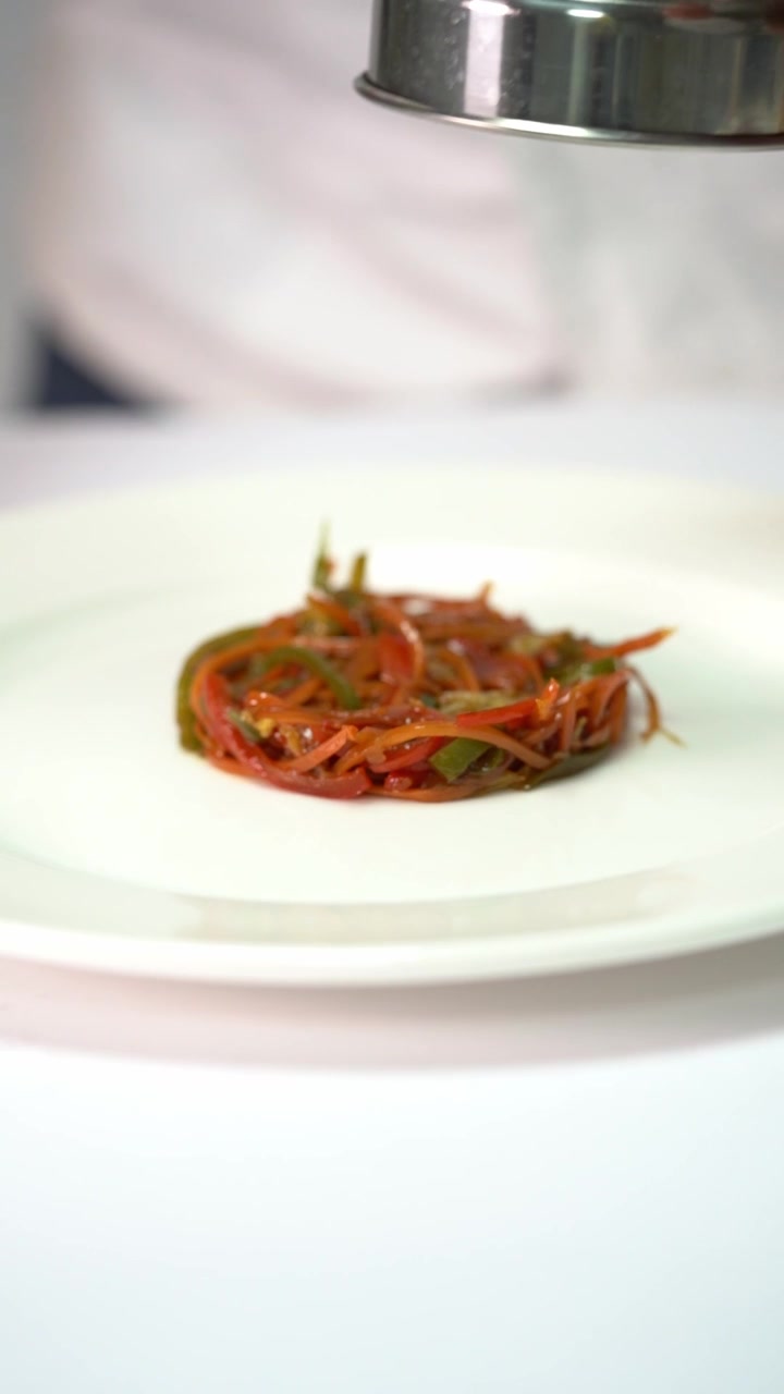 Chief plating a gourmet dish with vegetables and meat in a minimalist style, close up shot, insert shot