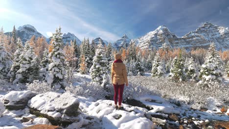 woman standing in snowy landscape looking at valley of the ten peaks