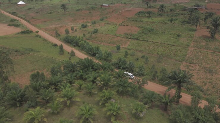 Drone shot of a white bus or van driving on a rocky road near the rural town of Kimina Bujumbura Burundi Africa on a warm day going closer to the subject LOG