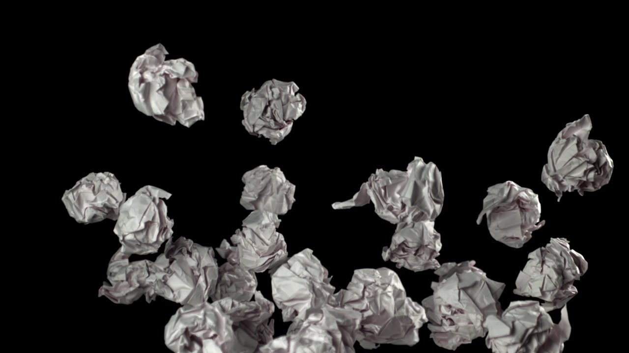 Palline di carta accartocciate che cadono e si accumulano su sfondo nero