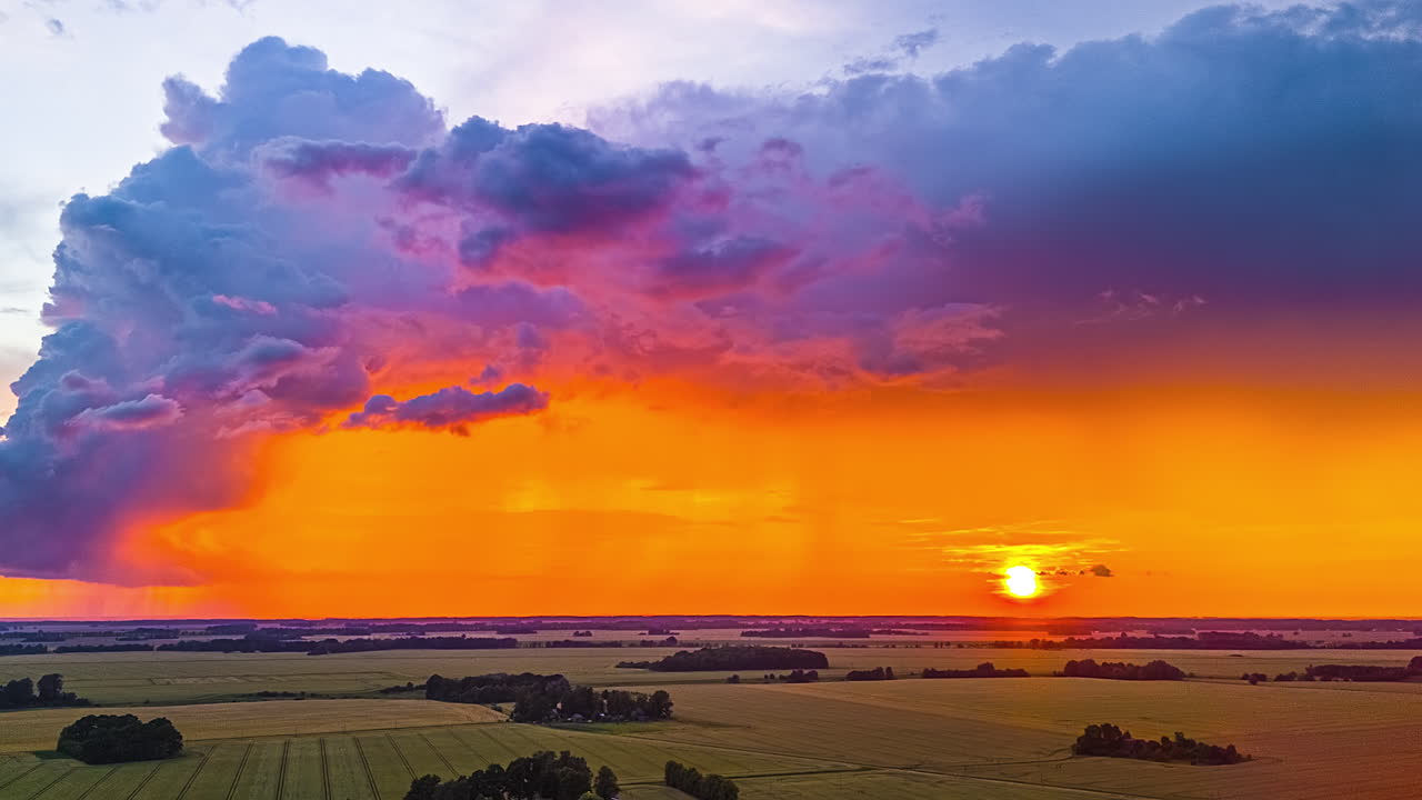 Cloudscape Against Warm Hues As The Sun Descends Over Countryside Fields. Timelapse