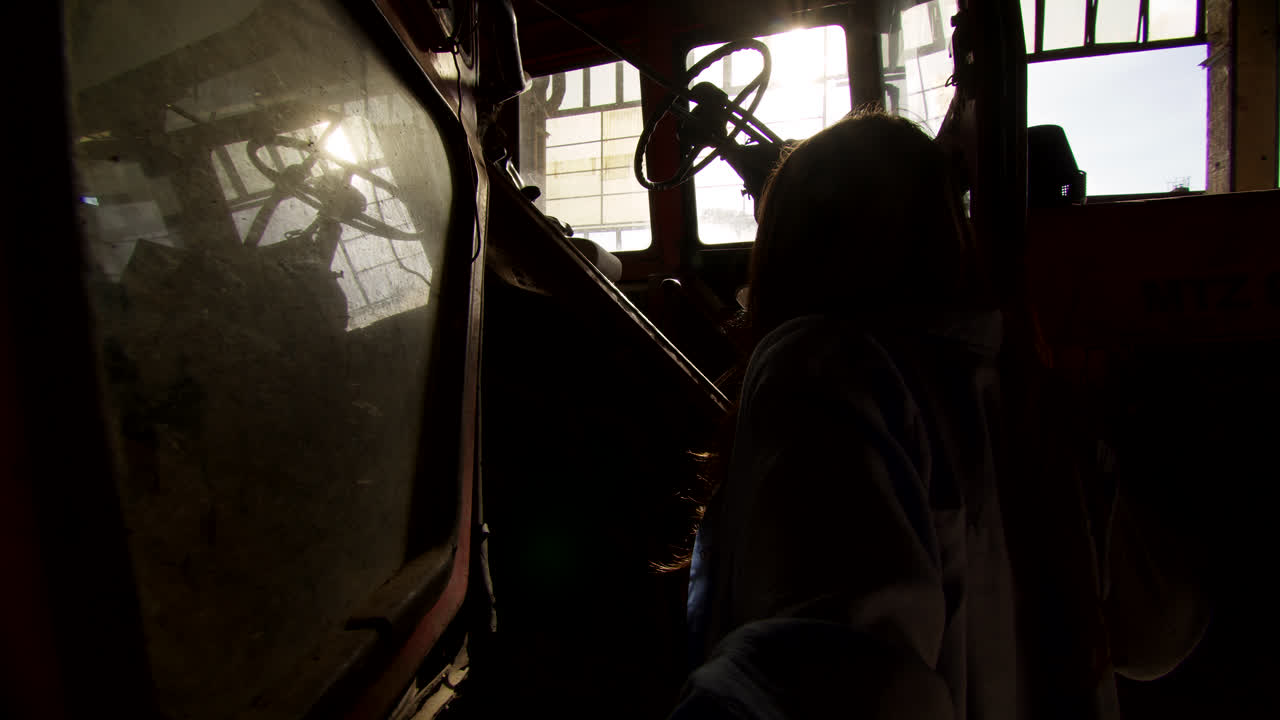 Woman Inspecting an Old Tractor in a Warehouse