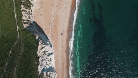 birdseye drone dolly over durdle door revealing limestone arch and stunning coastline below