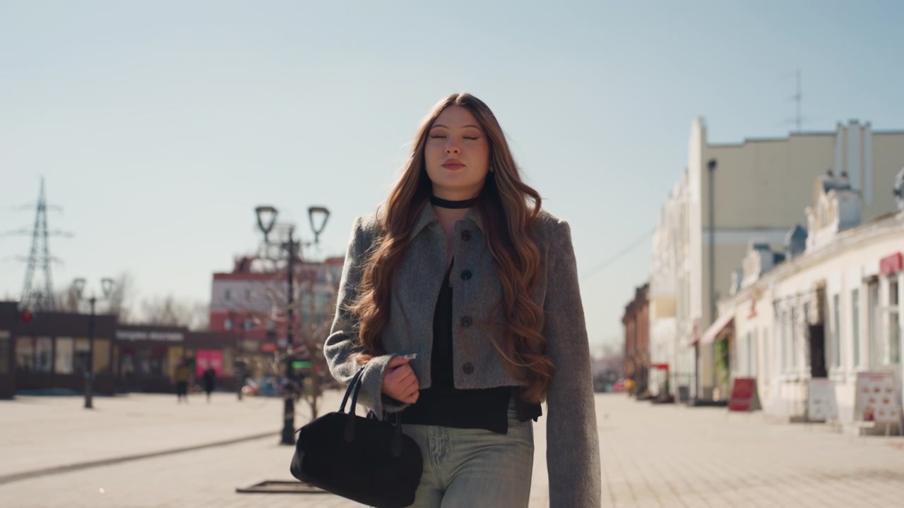 Donna elegante sta con sicurezza in ambiente urbano durante l'inverno. Donna sofisticata con cappotto e borsa alla moda assume una posa contemplativa tra le vetrine urbane in atmosfera invernale.