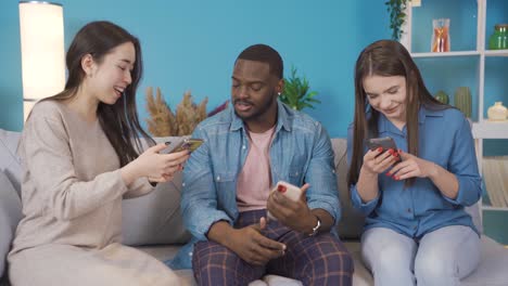 young people of different races are using phone at home and showing phone to each other.