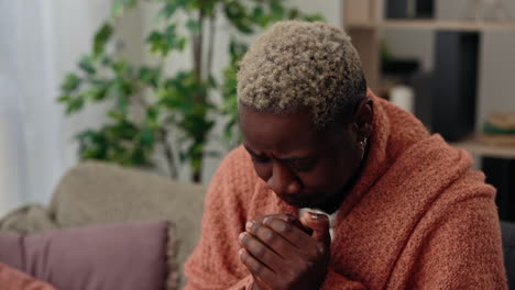 man feeling unwell, wrapped in a robe on the couch