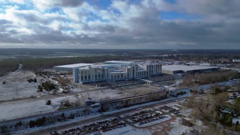 Large distribution center with loading docks and parking lot under a cloudy sky in winter. Spectacular aerial view flight drone top down Above view