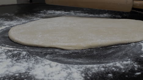 manos femeninas extiende la masa usando la cocina del rodillo