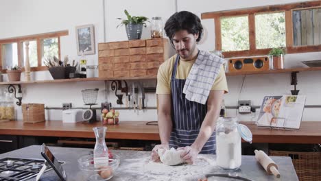 Hombre-Caucásico-Preparando-Masa-De-Pan-Usando-Tableta-En-La-Cocina,-Cámara-Lenta