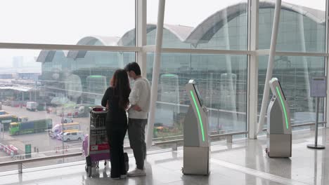 a couple enjoys the view from the departure hall terminal in hong kong international airport