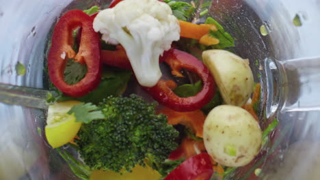 colorful raw vegetables blending inside blender in super slow motion close up.