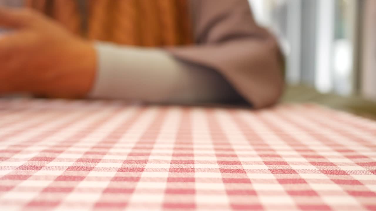 Woman holding smartphone at a restaurant table