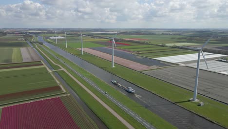 Día-Soleado-En-El-Campo-De-Holanda-Con-Canal-Y-Molinos-De-Viento,-Antena