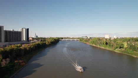 Lone-pontoon-boat-on-river-in-late-summer,-pretty-4K-drone-shot