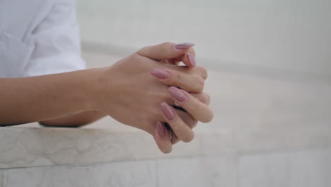 las manos de la mujer cruzan los dedos con un anillo elegante de cerca. brazos con manicura desnuda