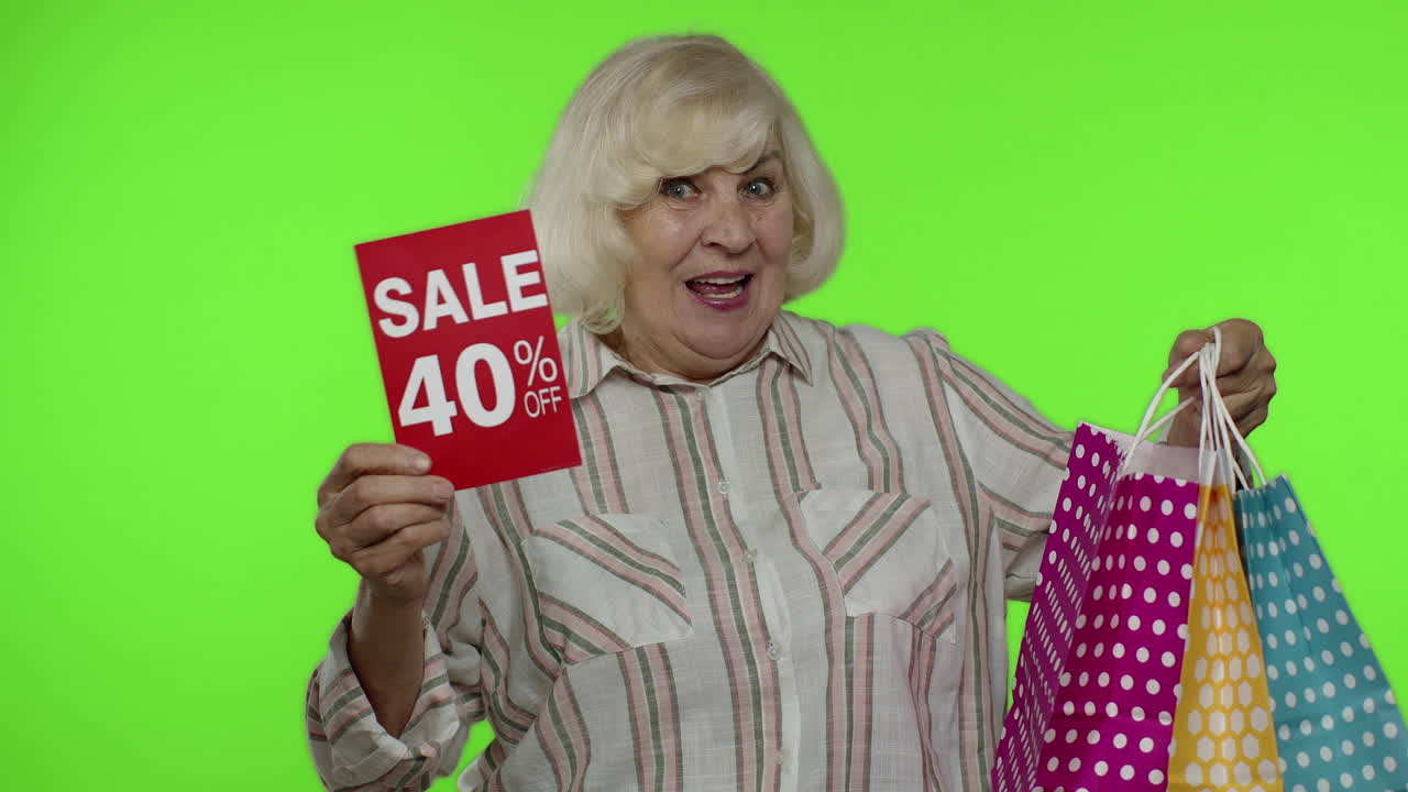 Senior woman showing Up To 40 percent Off inscription sign and shopping bags. Chroma key background