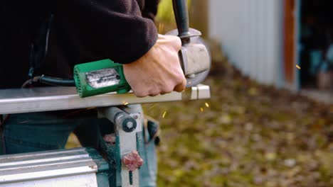 a married man cutting metal with angle grinder with sparks flying around in slowmotion