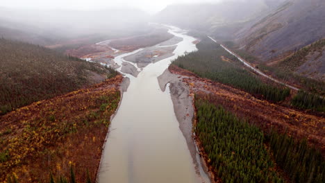 aerial view of ogilvie river, mountain and forest during autumn on a foggy day in yukon, canada.