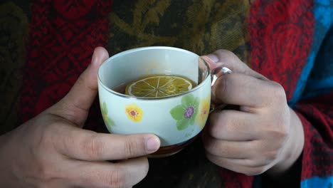 woman holding a cup of tea with lemon