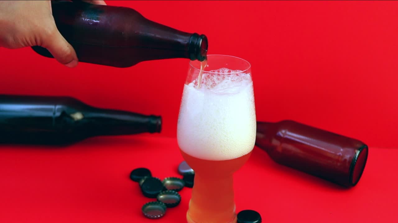 Kırmızı Arka Planda Beyaz Köpüklü Bardağa Altın Rengi Bira Dökülmesi
