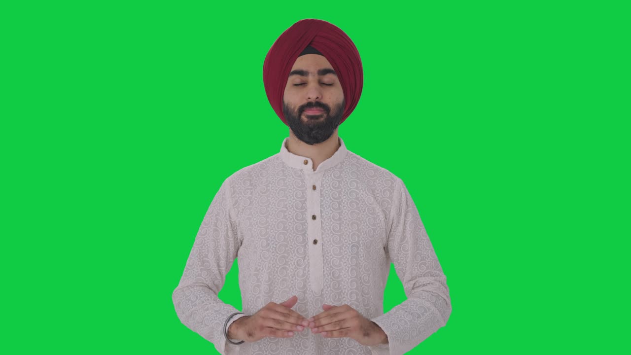 Uomo indiano Sikh che fa yoga su schermo verde.