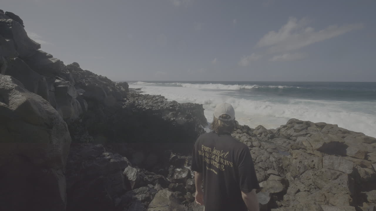 Man standing on the rocks overlooking the ocean waves
