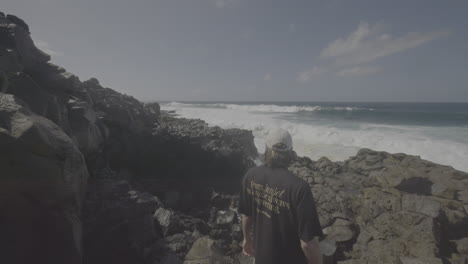 man standing on the rocks overlooking the ocean waves