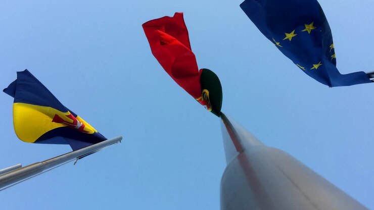 Bandiere di UE Unione Europea Portogallo isola di Madeira che sventolano al vento con sfondo cielo blu pennone