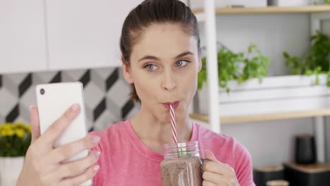 female blogger drinking fruit smoothie at kitchen