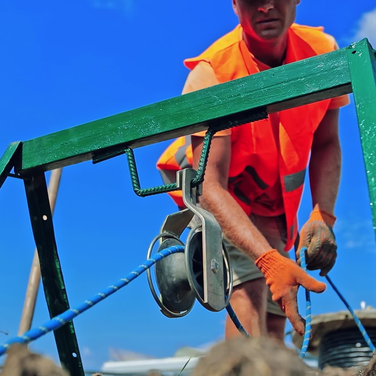 Construction industry on the field. Worker in orange uniform on blue sky background. Engineering works. Slow motion.