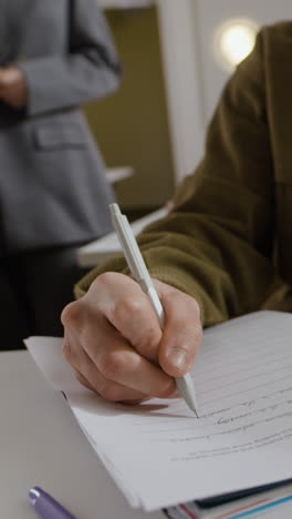 person writing on paper in a classroom