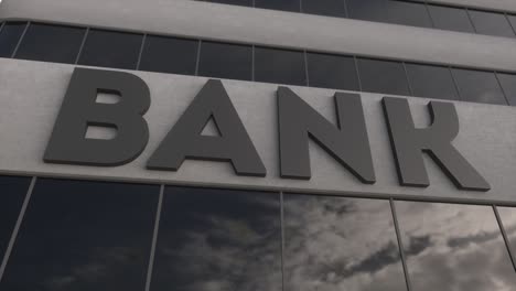 bank sign on a modern glass skyscraper. mirrored sky and city on modern facade. business and finance concept