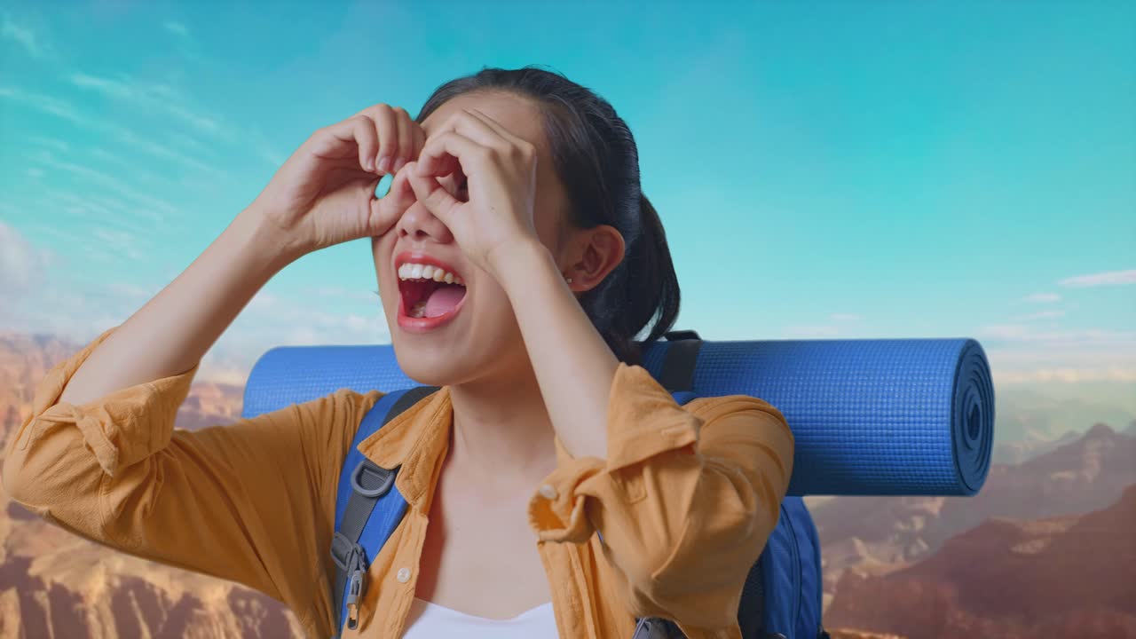 Close Up Of Asian Female Hiker With Mountaineering Backpack Making Binoculars Gesture Looking At Something Then Saying Wow While Traveling At The Top Of Mountain