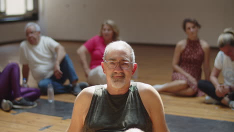 senior man sitting in dance studio and looking at camera