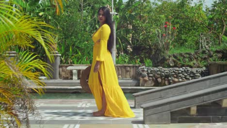 una niña con un vestido amarillo fluido caminando a través de los exuberantes jardines y la piscina de un majestuoso castillo