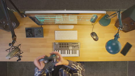 vista aérea de un músico masculino en una estación de trabajo con teclado y micrófono en el estudio