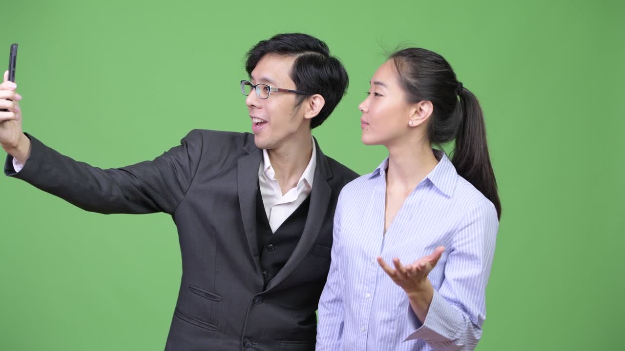 Young Asian business couple showing phone together