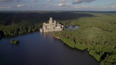 aerial dolly shot of the beautiful castle of stobnica, poland - a big tourist attraction built on an artificial island on a lake in the middle of an unhabituated forest