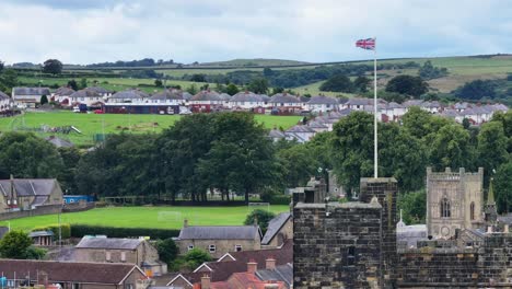 Toma-De-Drone-De-La-Bandera-Británica-Ondeando-En-La-Cima-De-La-Torre-Del-Castillo-De-Alnwick,-Inglaterra,-Reino-Unido,-60-Fps.