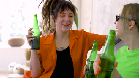 girl friends drinking beer, talking and laughing on a sofa at home