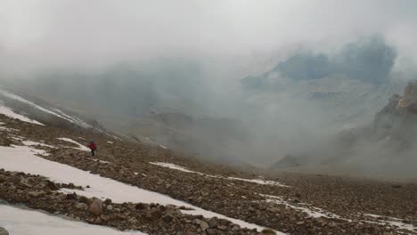 mochilero turístico en las nubes que descienden de la montaña, alto atlas, marruecos