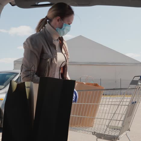 shopping during the epidemic - a woman puts bags of food in the trunk of a car